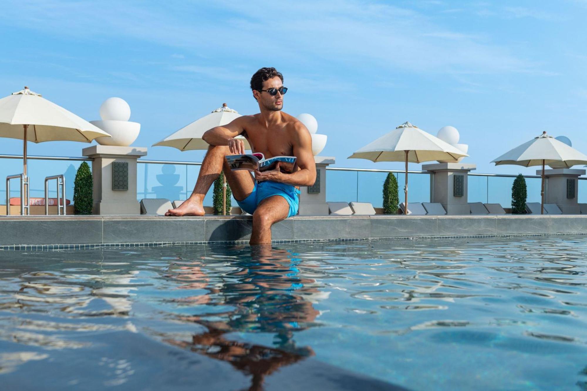 迪拜阿联酋购物中心喜来登酒店 外观 照片 A man sitting on the edge of a pool